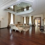 Nowoczesny salon z sofą, drewnianą podłogą i żyrandolem над dywanem