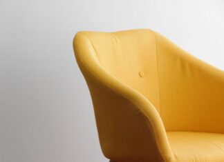 5 sygnałów, że designerski mebel to replika niskiej jakości Żółty designerski fotel na tle białej minimalistycznej ściany